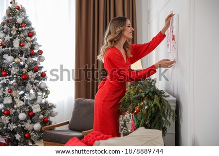 Young woman with picture decorating room for Christmas