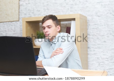 Photo of a businessman working on a modern loft office. Man sits on wooden table and uses modern laptop