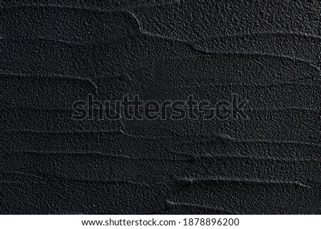 Black concrete wall in a modern style lit with soft light and its surface in wave relief. Elegant pattern. Royalty-Free Stock Photo #1878896200