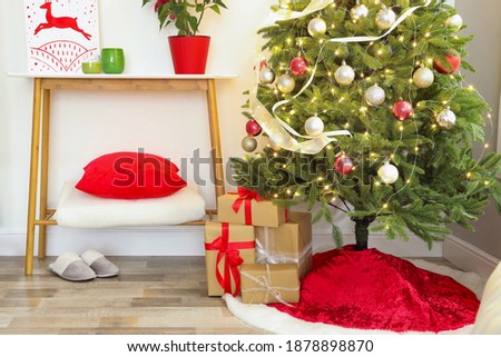 Beautiful Christmas tree with red skirt indoors