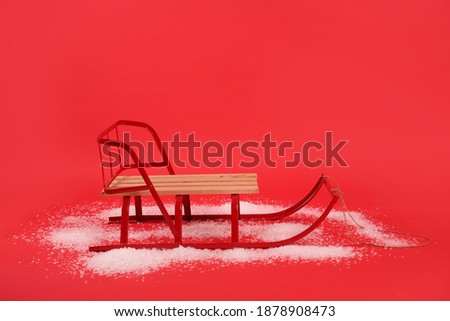 Empty sleigh and snow on red background