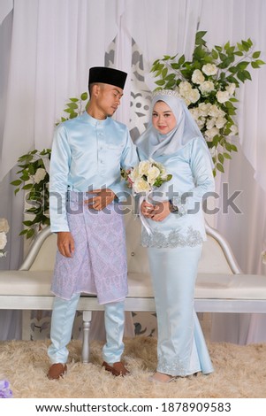 Bride and groom wearing baby blue Malay traditional cloth pose during wedding celebration in Malaysia