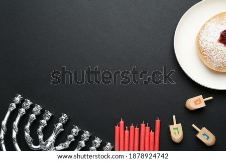 Hanukkah traditional menorah, candles, doughnut and dreidels with letters He, Pe, Nun, Gimel on black background, flat lay. Space for text