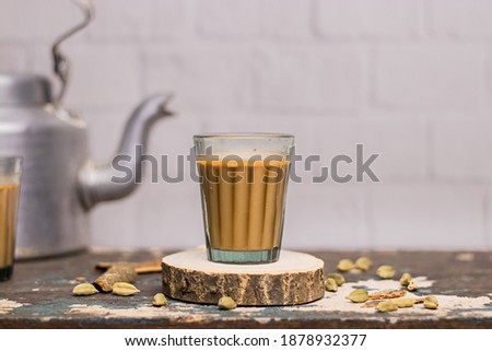 Indian chai in glass cups with metal kettle and other masalas to make the tea.  Royalty-Free Stock Photo #1878932377