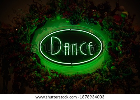 Green neon dance sign against dark background