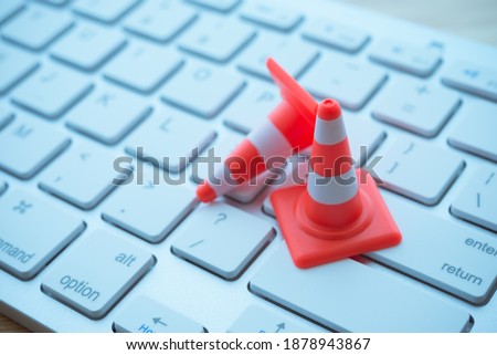 Maintenance, repair, under construction in computer system from virus or ransomware concept. Close up orange white traffic warning cones or pylon on keyboard computer background with copy space. Royalty-Free Stock Photo #1878943867