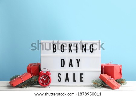 Composition with Boxing Day Sale sign and Christmas gifts on white table against light blue background
