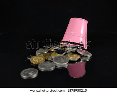 Selective focus.Picture of a Savings and Finance idea concept.Coins and pink bucket with black background.Shot were noise and film grain in full resolution.