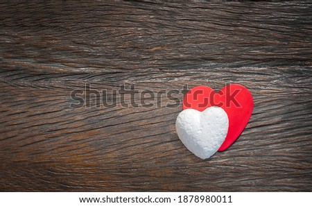 couple of hearts on wooden background. white and red hearts on dark wooden background