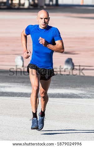 Vertical photo of a man in sportswear running in the street. Sport concept