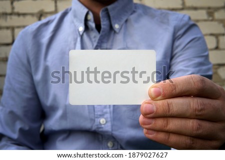 Business man handing a blank business card over background white brick wall on the street. A plastic credit card or business card as a mockup for design or text with an empty space.