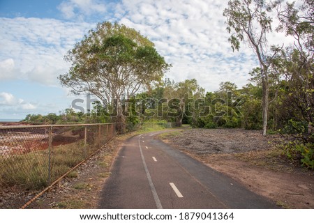 Remote bicycle path on fenced coastline at the East Point Reserve with lush greenery in Darwin, Australia
