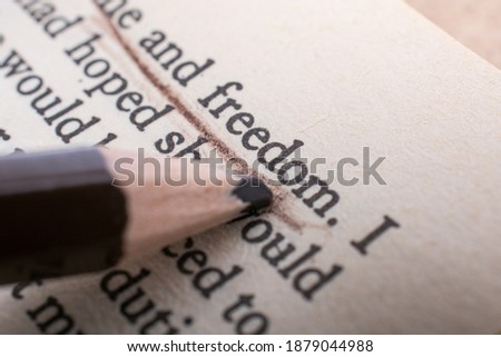 A closeup shot of a pencil underlining and pointing at the word Freedom Royalty-Free Stock Photo #1879044988