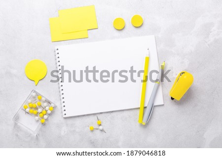 Office workplace with notepad and stationery accessories on gray stone background. Yellow stationery. Flat lay. Top view - Image