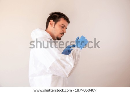 An adult male doctor wearing latex gloves and personal protective equipment for COVID-19