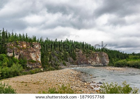 Large sheer cliff overgrown with forest in the Ural mountains on a summer day