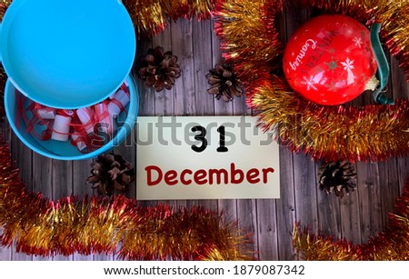 December 31 on a yellow sticker.Christmas balloon, fir cones on a wooden background.The first month of winter.Calendar for December.