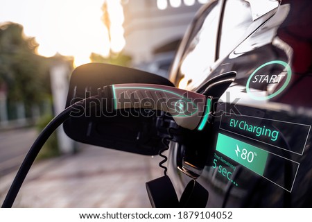 Power cable pump plug in charging power to electric vehicle EV car with modern technology UI control information display, car fueling station connected power cable alternative sustainable eco energy Royalty-Free Stock Photo #1879104052