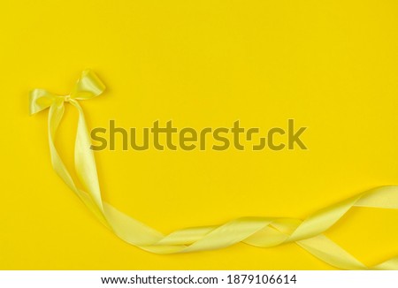 yellow satin ribbon bow on a yellow background.trending colors 2021