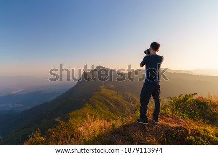 Photographer over Doi Pha Tang viewpoint photographing beautiful landscape view located in Chiang Rai province, Thailand