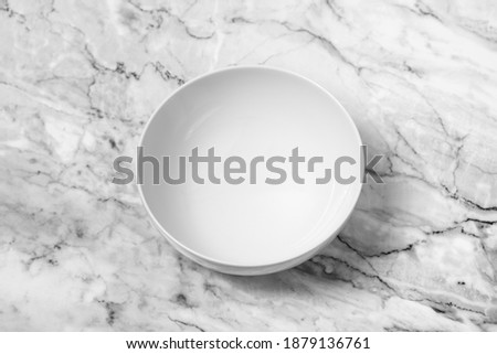 An empty white plate on marble table.