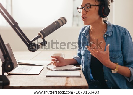 Young woman recording and broadcasting her podcast from home. Female working from home and running her radio show.