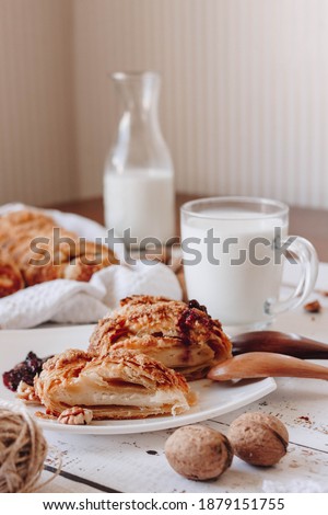 There are homemade cakes on the table, a cup of milk, and a half-empty bottle. in the foreground are walnuts. A soft picture.