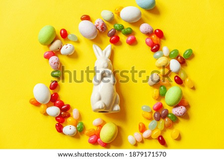 Happy Easter concept. Preparation for holiday. Easter candy chocolate eggs bunny and jellybean sweets isolated on trendy yellow background. Simple minimalism flat lay top view copy space