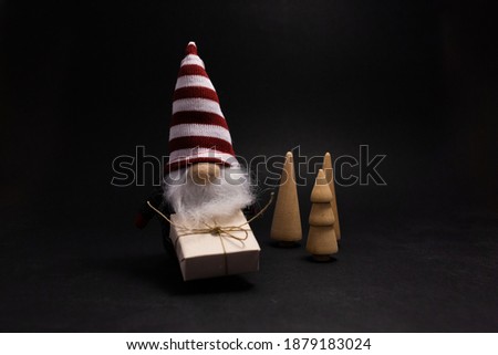 Christmas trees and Santa Claus with christmas present wrapped in craft paper on black background. Close up.