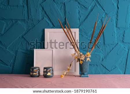 candlesticks, decoration of reed cones and photo frames standing on the table, on a blue background