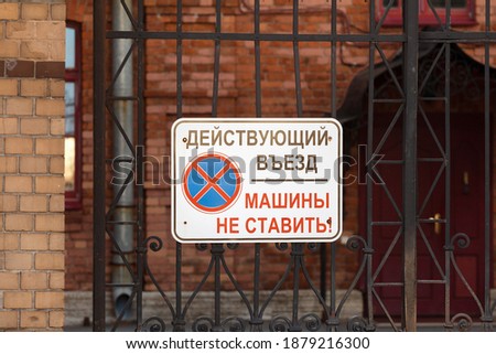 A sign on the metal gates of a brick house with an inscription in Russian: Do not park cars