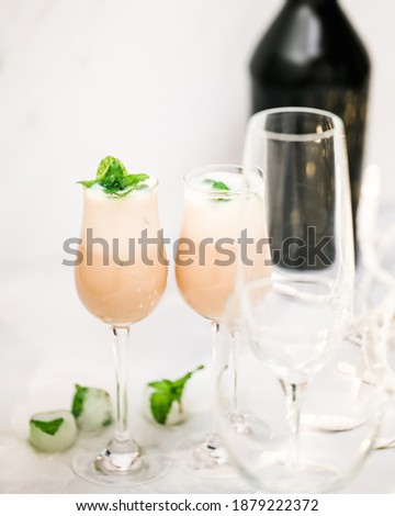 Cream liquor with frozen ice mint leaves close up in glasses on light background, vertical banner