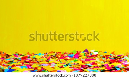 Close-up of a ground full of confetti with a yellow background. Carnival and party concept. Horizontal photography. Copy Space