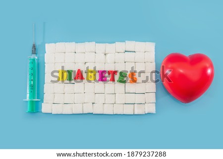 Heart, syringe and the word diabetes on sugar cubes. World Diabetes Day. Blue background.