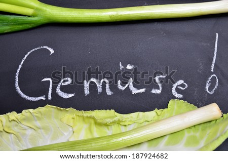 Bio blackboard fresh vegetables on wooden board with the German word "Gemuese", translation: vegetables