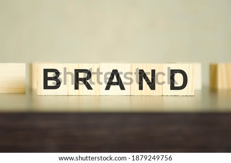  TEXT BRAND WRITTEN ON WOODEN CUBES AND STAND ON DARK BACKGROUND. High quality photo