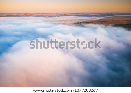 Agricultural lands are covered with thick fog in the morning. Location place Dniester canyon of Ukraine, Europe. Aerial photography, drone shot. Vibrant photo wallpaper. Discover the beauty of earth.