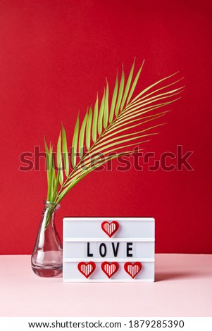 Love lightbox message with red hearts and palm leaf on pink and red background