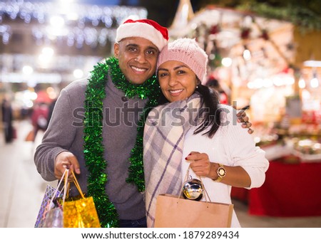 Positive adult couple buying decoration at Christmas Fair outdoor
