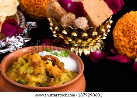 Close Up Details Of Delicious Daliya Dal Khichdi Served In Traditional Indian Matka With Curd And Til Gul Gur Ke Gajak And Floral Decoration. Makar Sankranti Lohri Pongal Celebration Theme Of Hindu