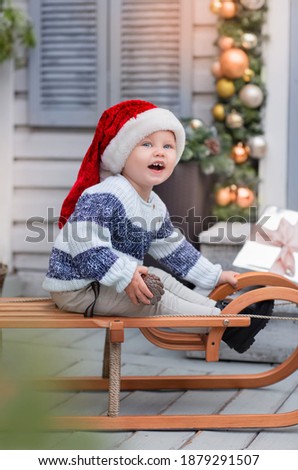 Funny boy on the winter porch in a santa hat
