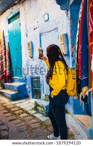 a woman taking a picture with her phone on one of the streets of morocco