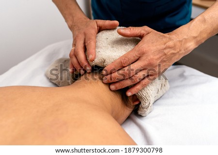 Stock photo of unrecognizable woman giving back massage to patient lying in stretcher.