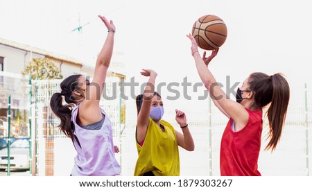 three basketball players jump up to catch the ball wearing masks