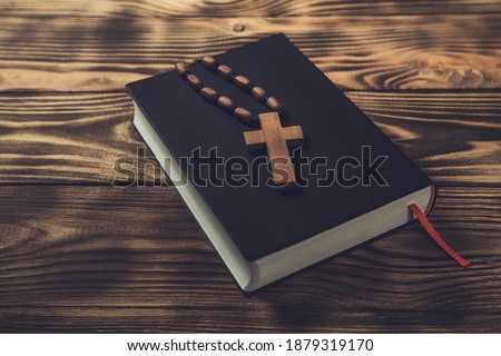 wooden cross on Holy Bible on wooden background