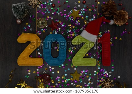 2021 New year. Knitted colored numbers and Christmas decorations on a dark wooden background.