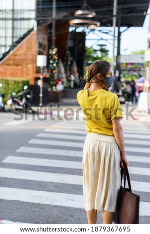 Woman yellow shirt gray protective mask on street of city. New rule. Travel concept. Wearing in two color of the 2021 year illumination yellow and ultimate gray. Protect from coronavirus