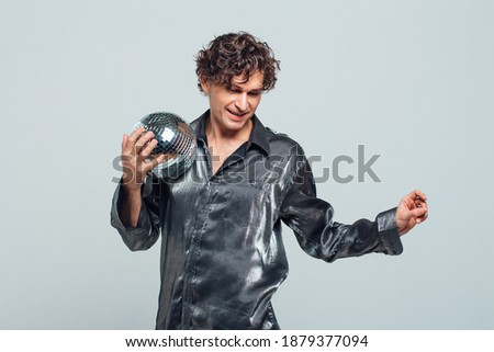 Portrait of tall attractive man with a mirror disco ball on a white background. Handsome man posing with a shiny disco ball in studio.