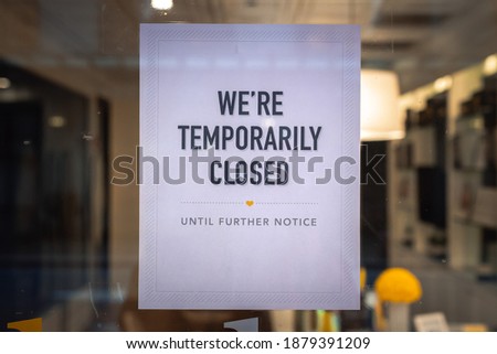 A printed sign is taped to a storefront business in downtown Chicago indicating the business is temporarily closed due to Covid-19 coronavirus pandemic.