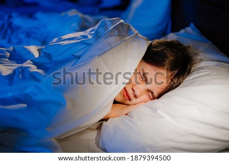 A girl naps in bed in her room, sees a nightmare in sleep. restless, unhealthy sleep in children after watching a horror movie, computer game. Royalty-Free Stock Photo #1879394500